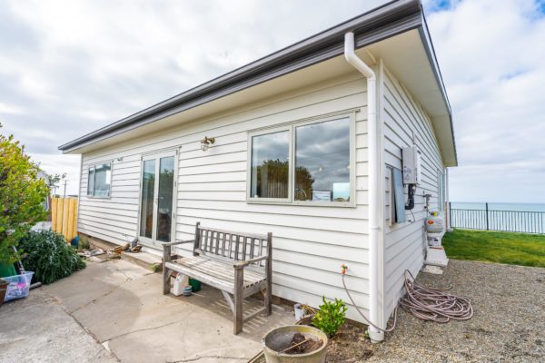 Exterior photo of bach after renovation which included new double glazed windows and doors, new weatherboard cladding and new foundations