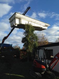 Crane lifting out old swimming pool in preparation for new pool and outdoor area including new paving