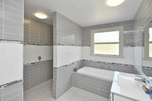 Bathroom renovation project completed with full wall tiles, new bath, sink unit