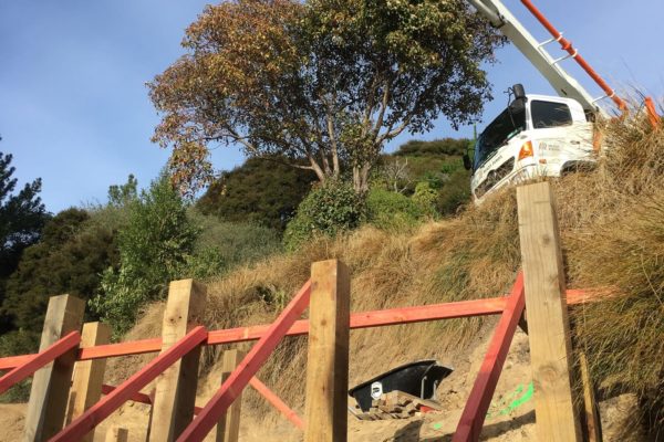 Concrete pump reaching downhill to lay concrete for new decking piles