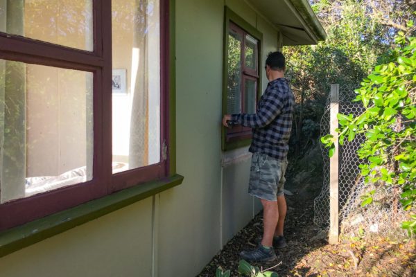 Code Construction measuring an exterior window frame in preparation for renovation project