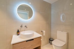 Single toilet renovation by Code Construction with new modern sink and cabinetry
