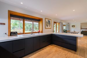 Kitchen renovation project completed by Code Construction. Showing new matt black kitchen with thick white bench top and large double sink