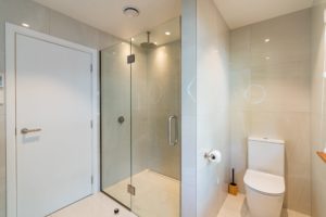 Completed renovated bathroom project by Code Construction featuring new modern waterfall shower and toilet